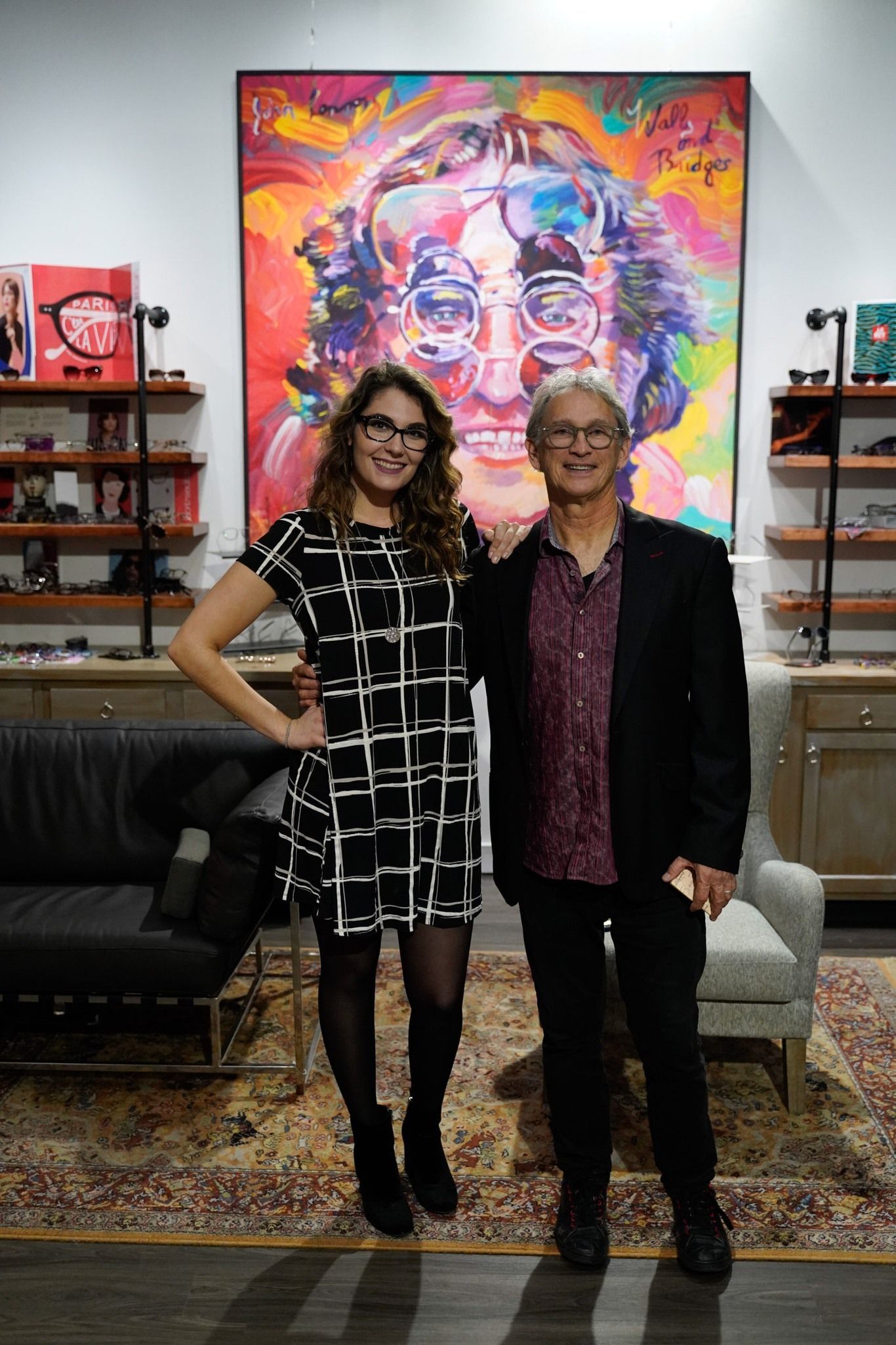 Samm Sawyer and Gregor Owen standing in CustomEyes shop, smiling at camera. Both wearing glasses