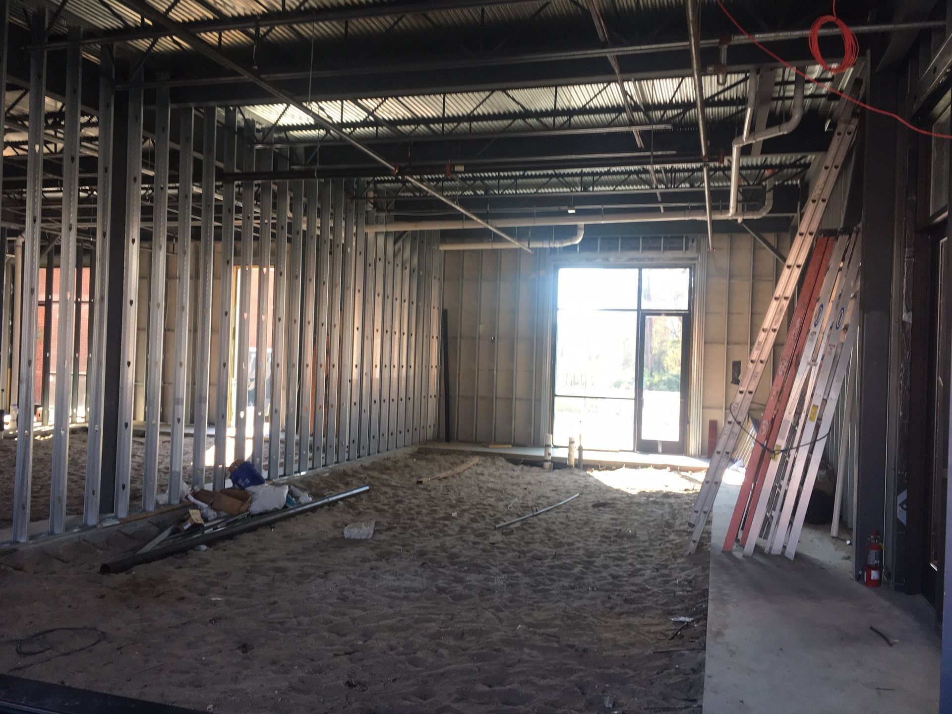 A building under construction with a ladder on the dirt ground