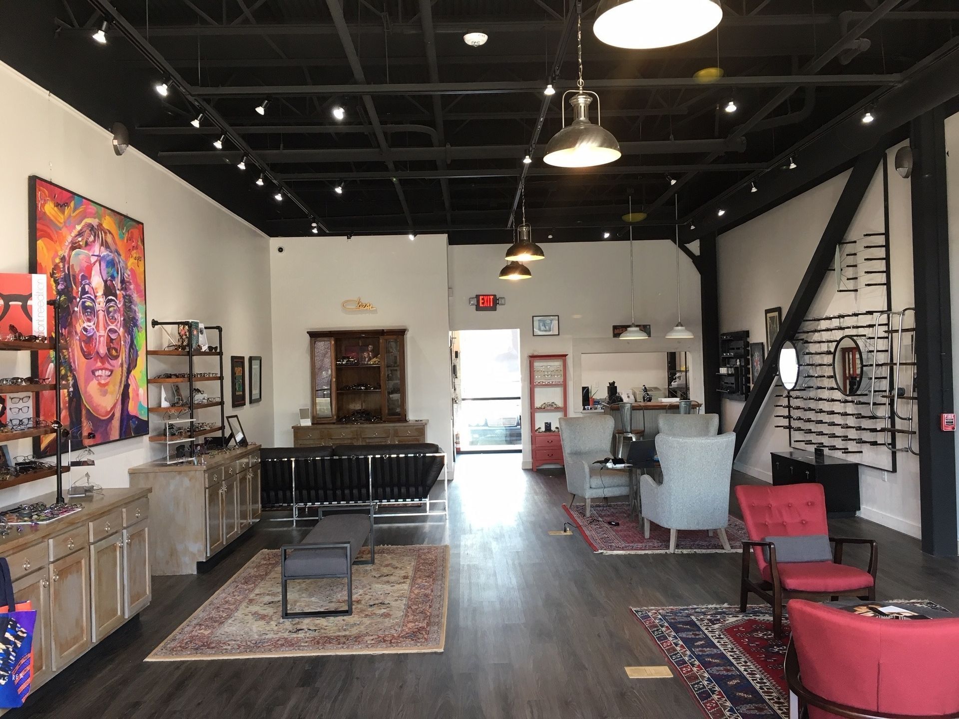 Interior CustomEyes eyewear shop with clean, updated flooring and walls, traditional rugs, pops of red, upcycled furniture, chic industrial shelving