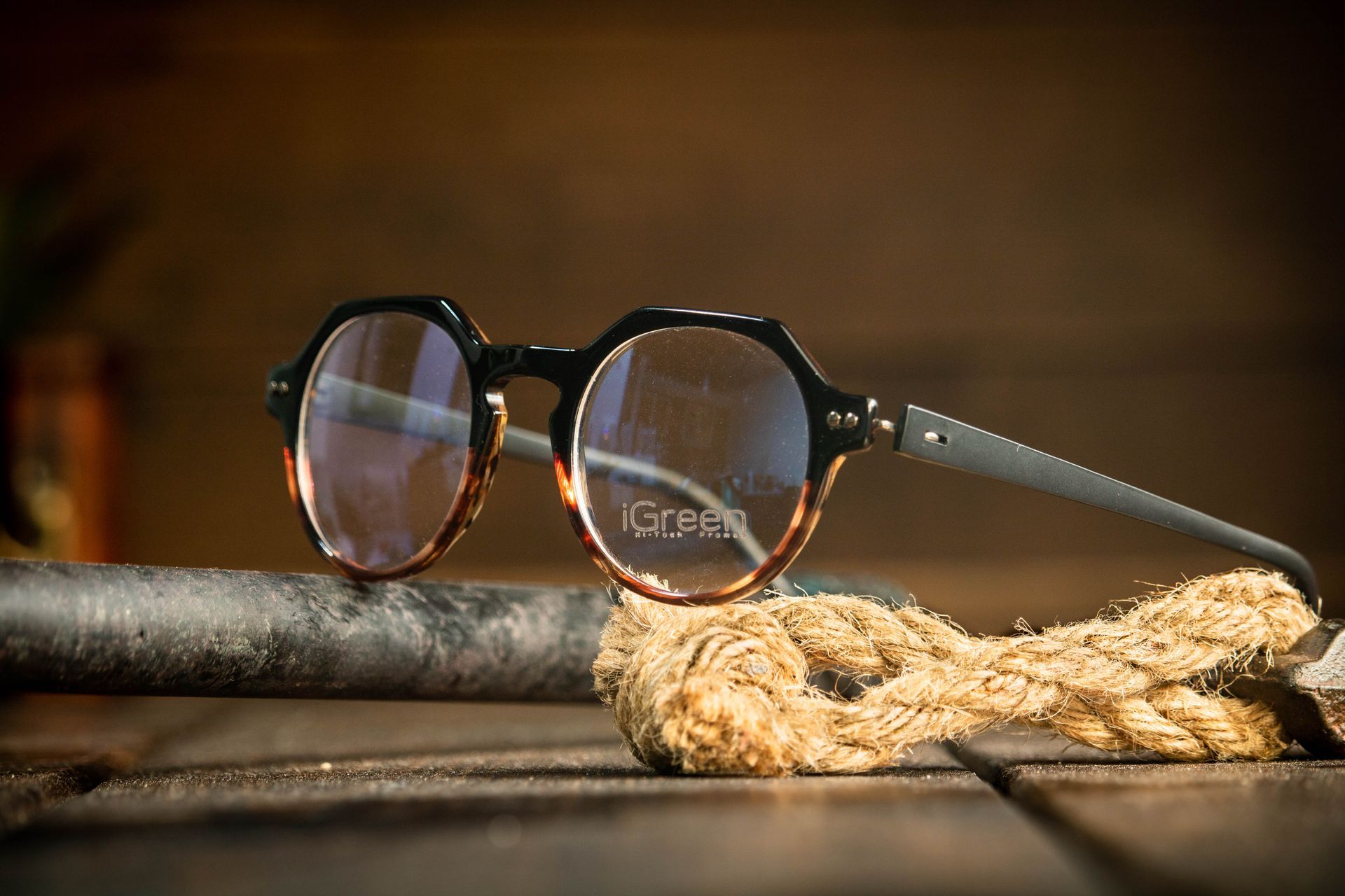 A pair of iGreen glasses sitting on top of a wooden table next to a rope.