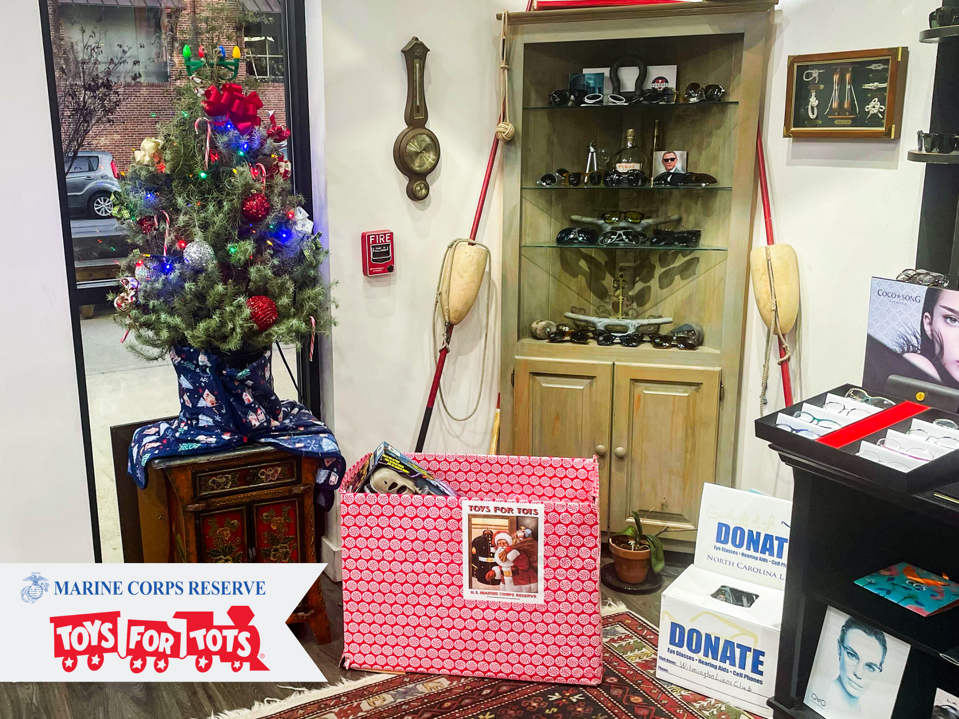 Christmas tree decorated with eyeglasses, a gift-wrapped Toys for Tots collection bin in CustomEyes