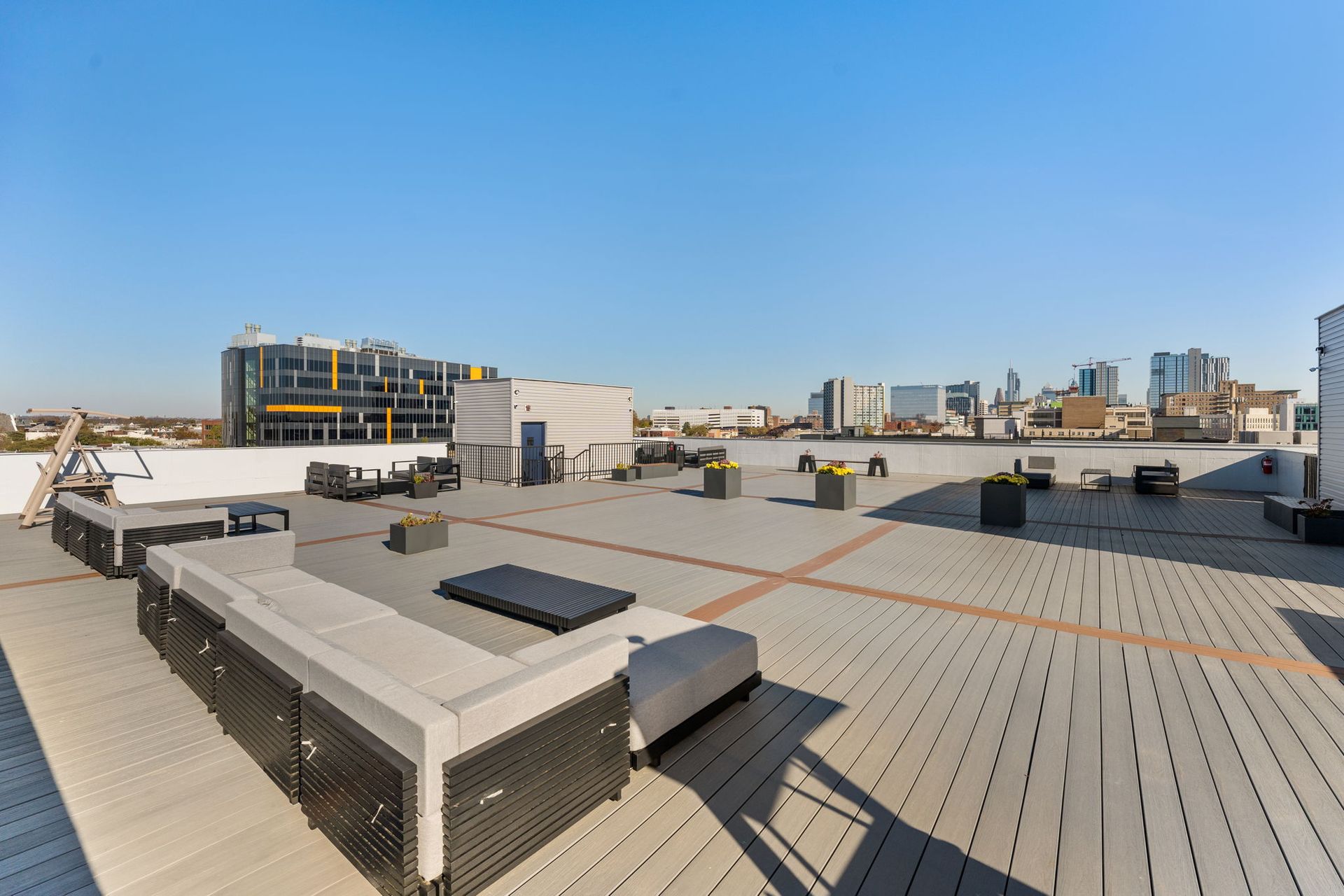 A rooftop deck with a couch and chairs and a view of the city.