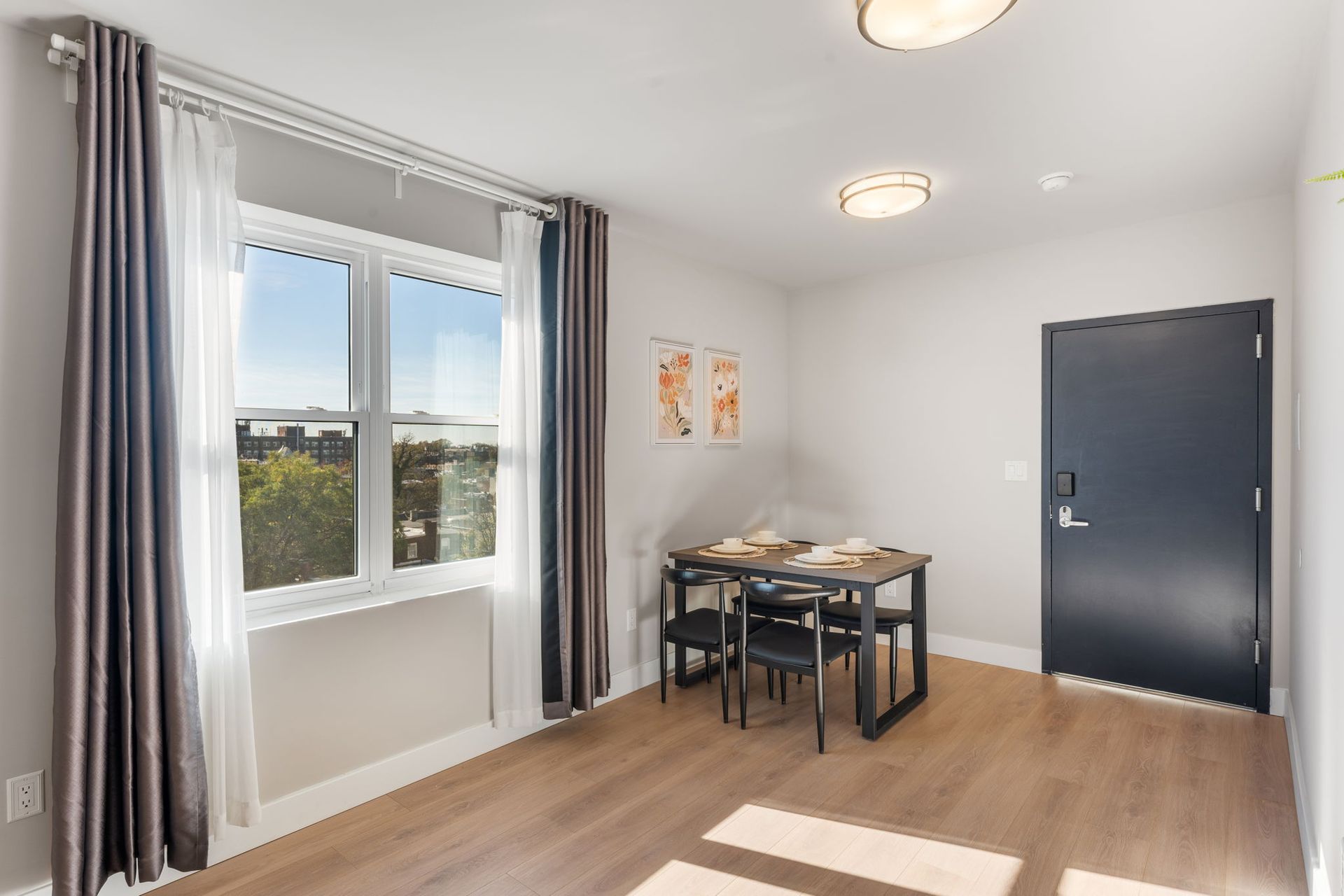 A living room with a dining table and chairs and a window.