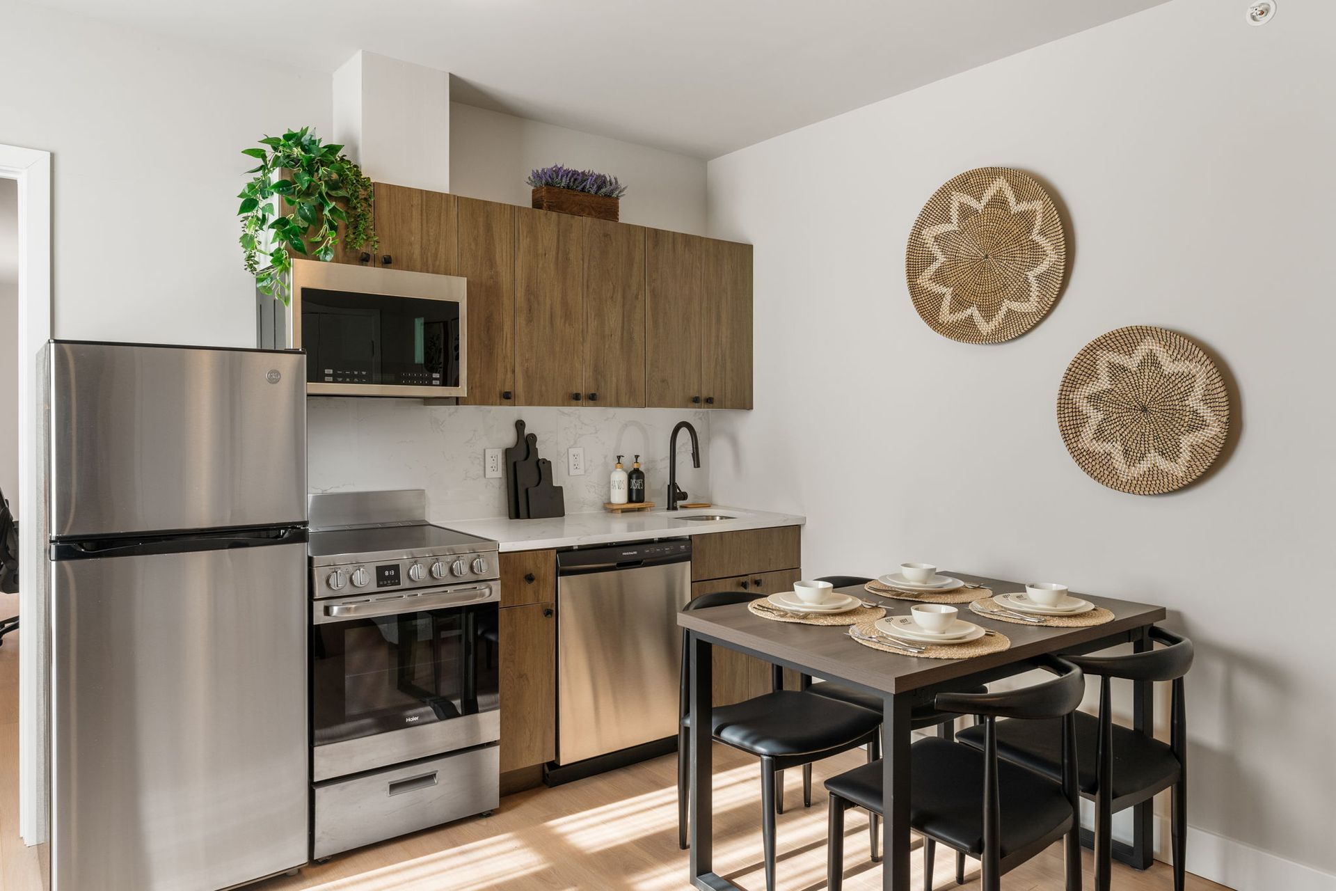 A kitchen with stainless steel appliances , wooden cabinets , a table and chairs.