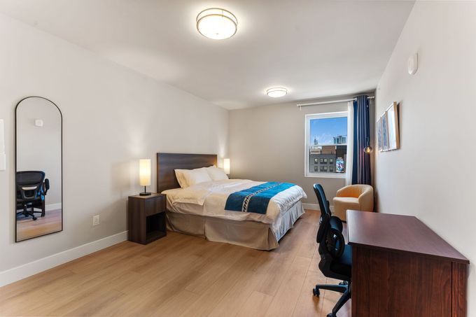 A yellow chair is sitting in front of a window in a bedroom.