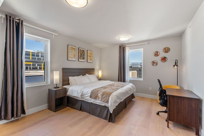 A bedroom with white sheets and orange pillows