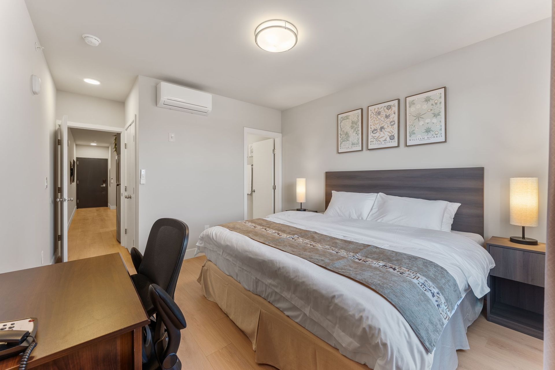 A hotel room with a king size bed , desk and chair.