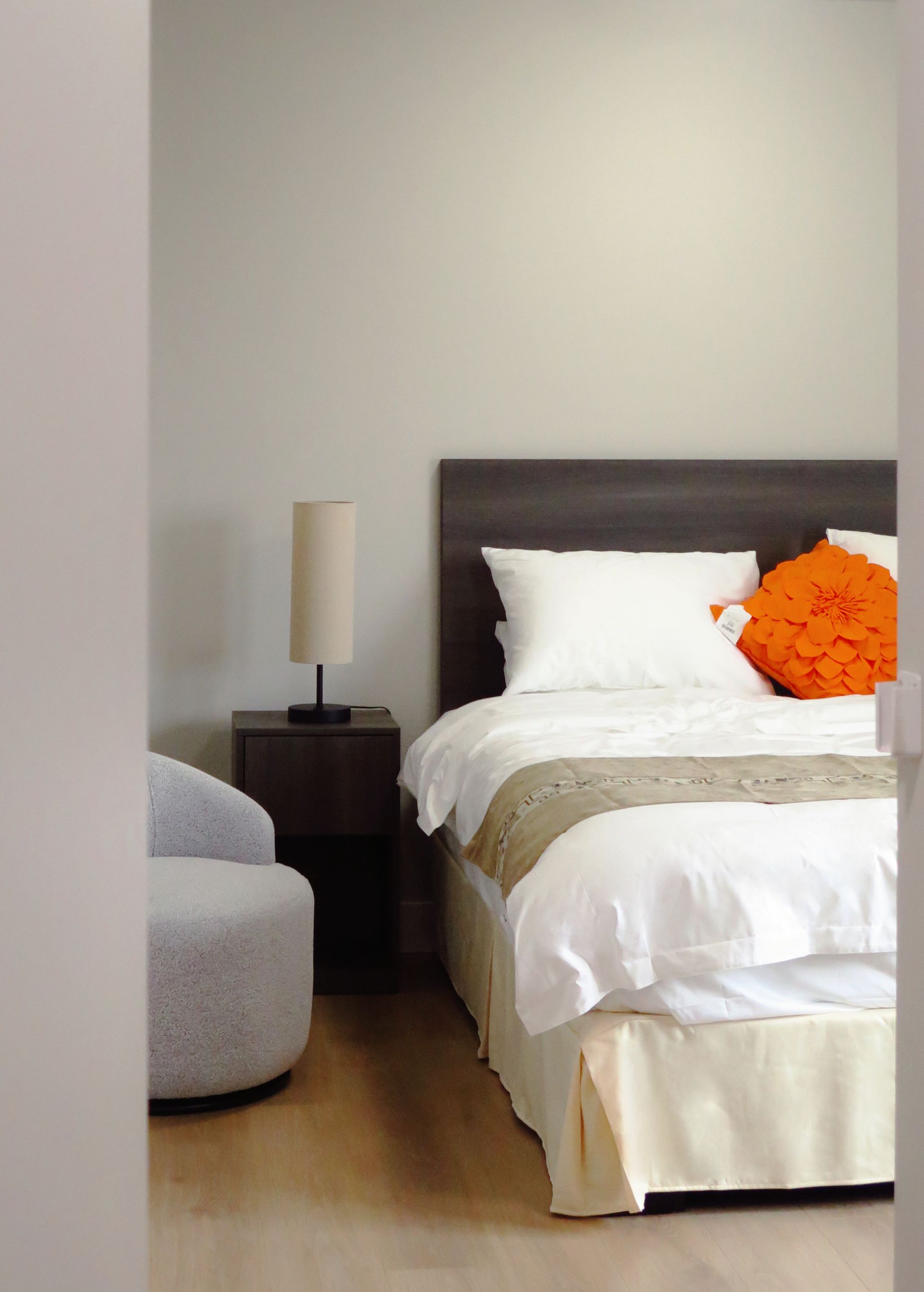 A bedroom with white sheets and orange pillows