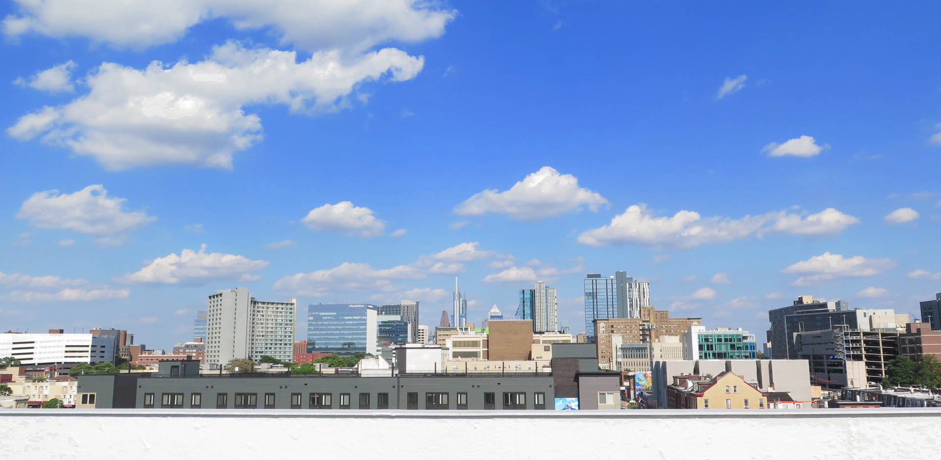 A city skyline with a blue sky and white clouds