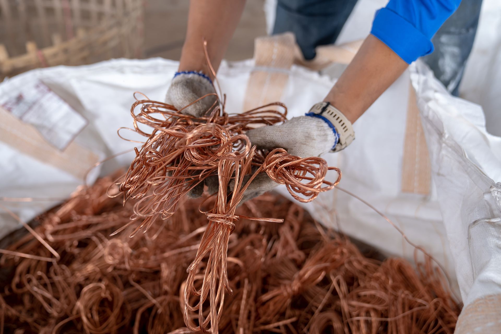 A worker at Ranch Town Metal Recycling Center in Salinas, CA, collecting scrap copper wire into a ba