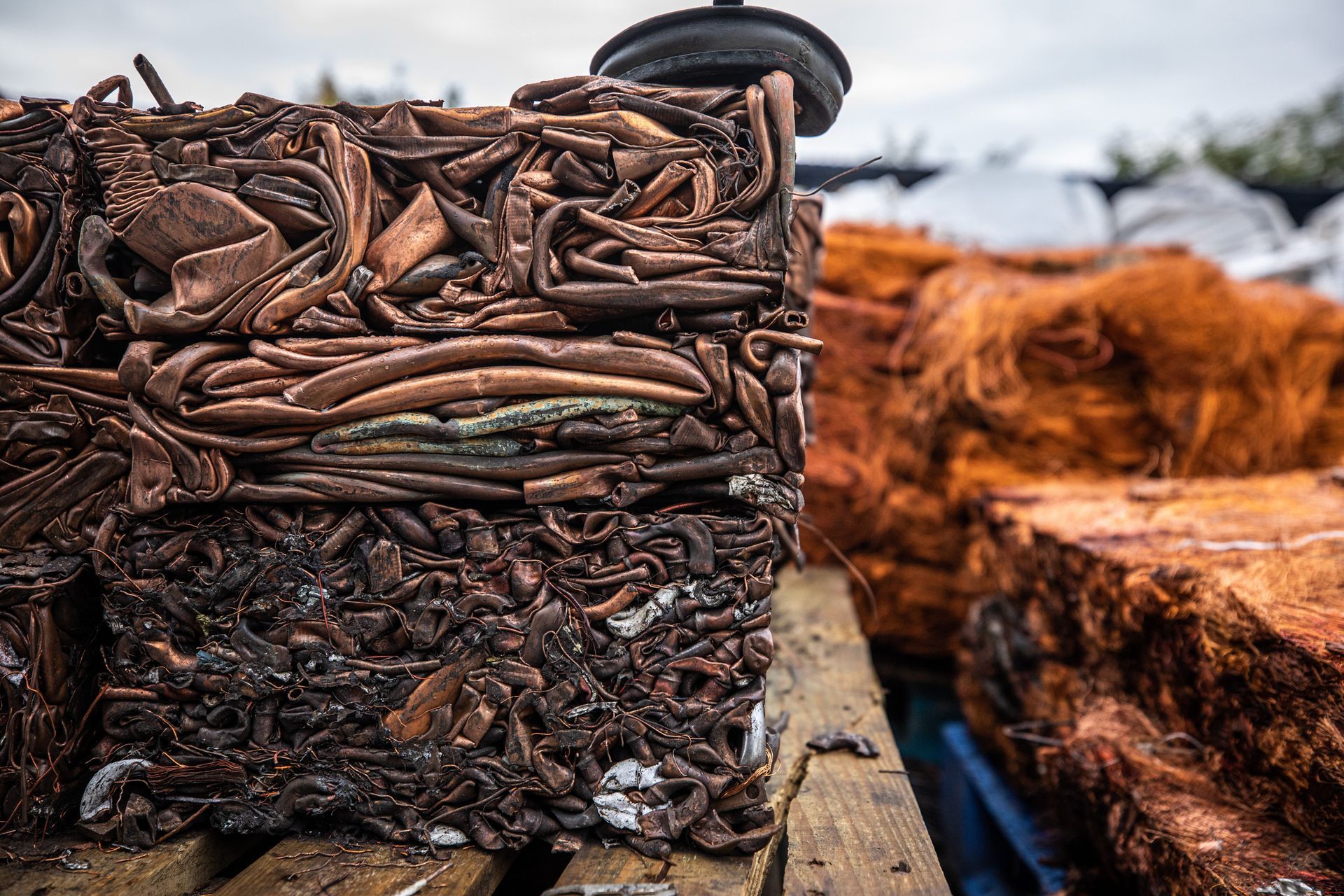 Close-up of crushed copper bales stacked on a pallet, for recycling at a metal recycling facility.
