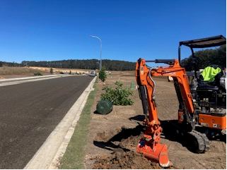 A Truck Is Driving Through A Dirt Field With An Excavator In The Background — Michael Flick Horticulture in Coffs Harbour, NSW