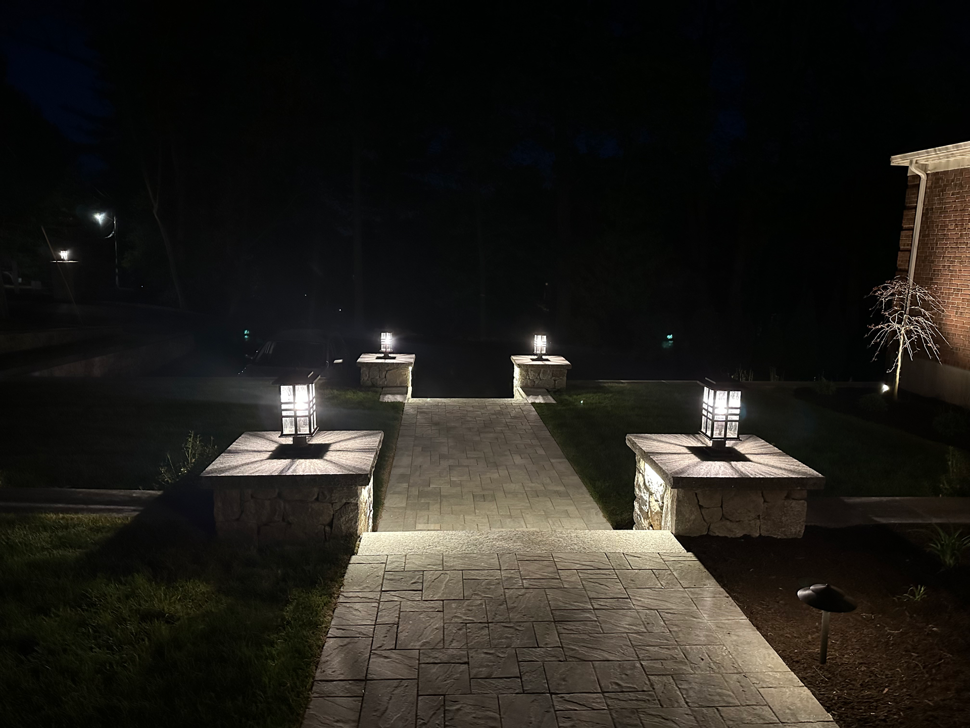 A brick walkway is lit up at night.