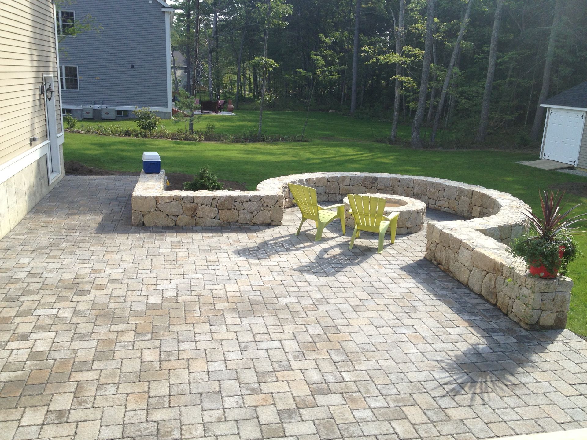 A patio with a fire pit and yellow chairs