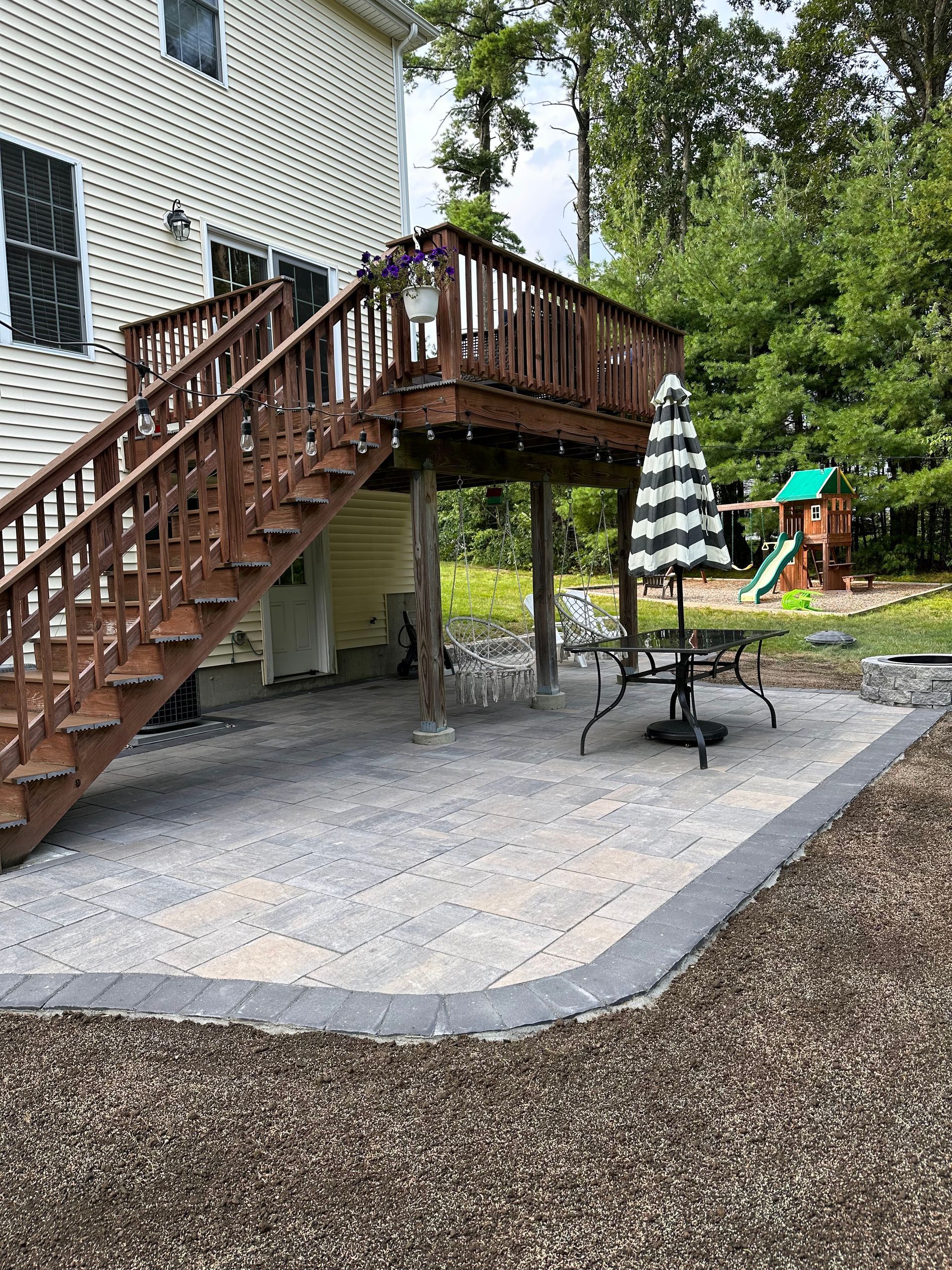 A lawn with chairs and an umbrella in the middle of it.