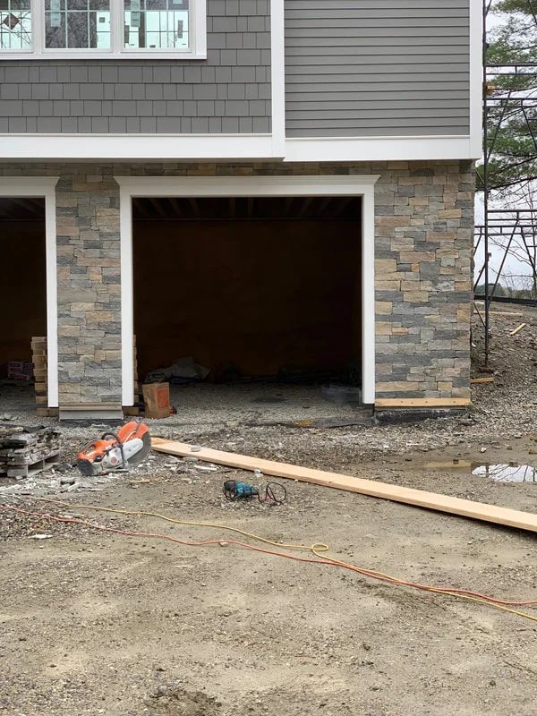 A garage door is open in front of a house under construction.