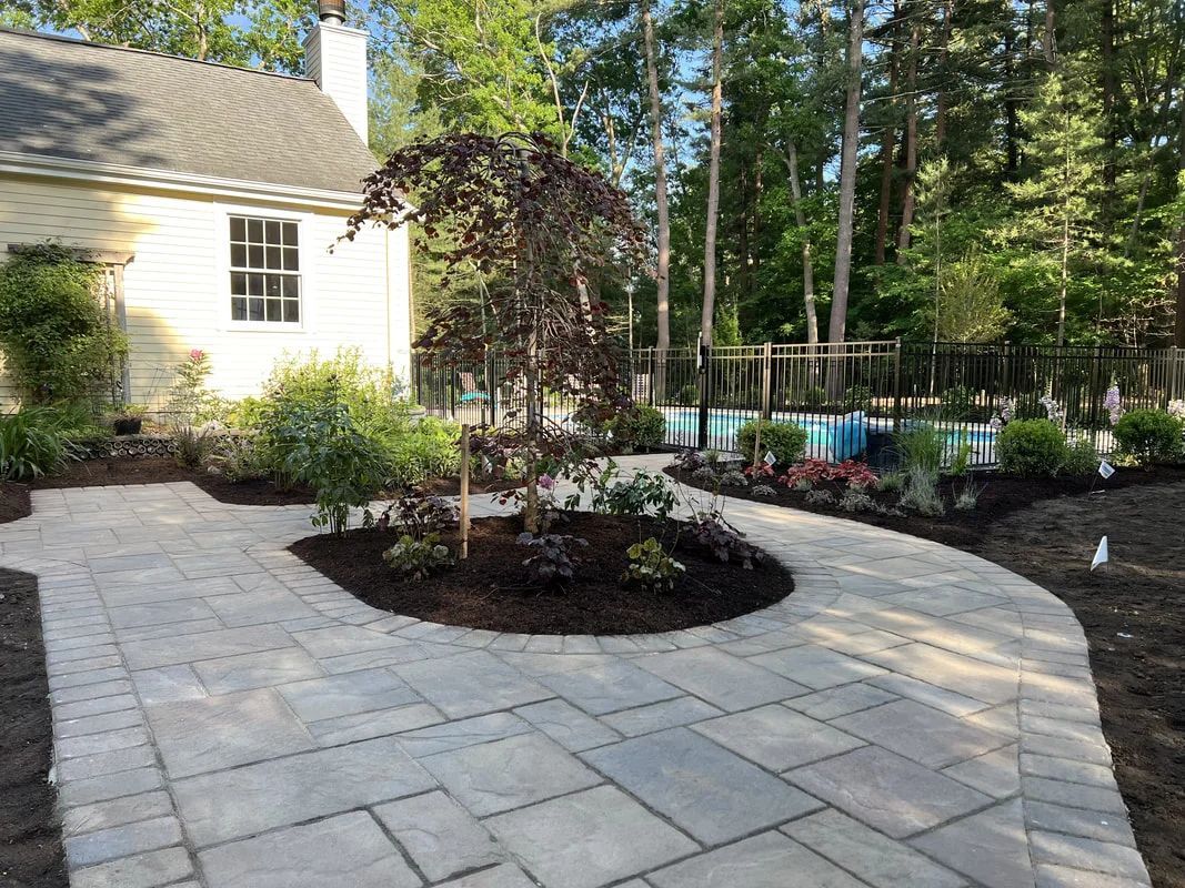 A patio with a walkway leading to a house and a pool.