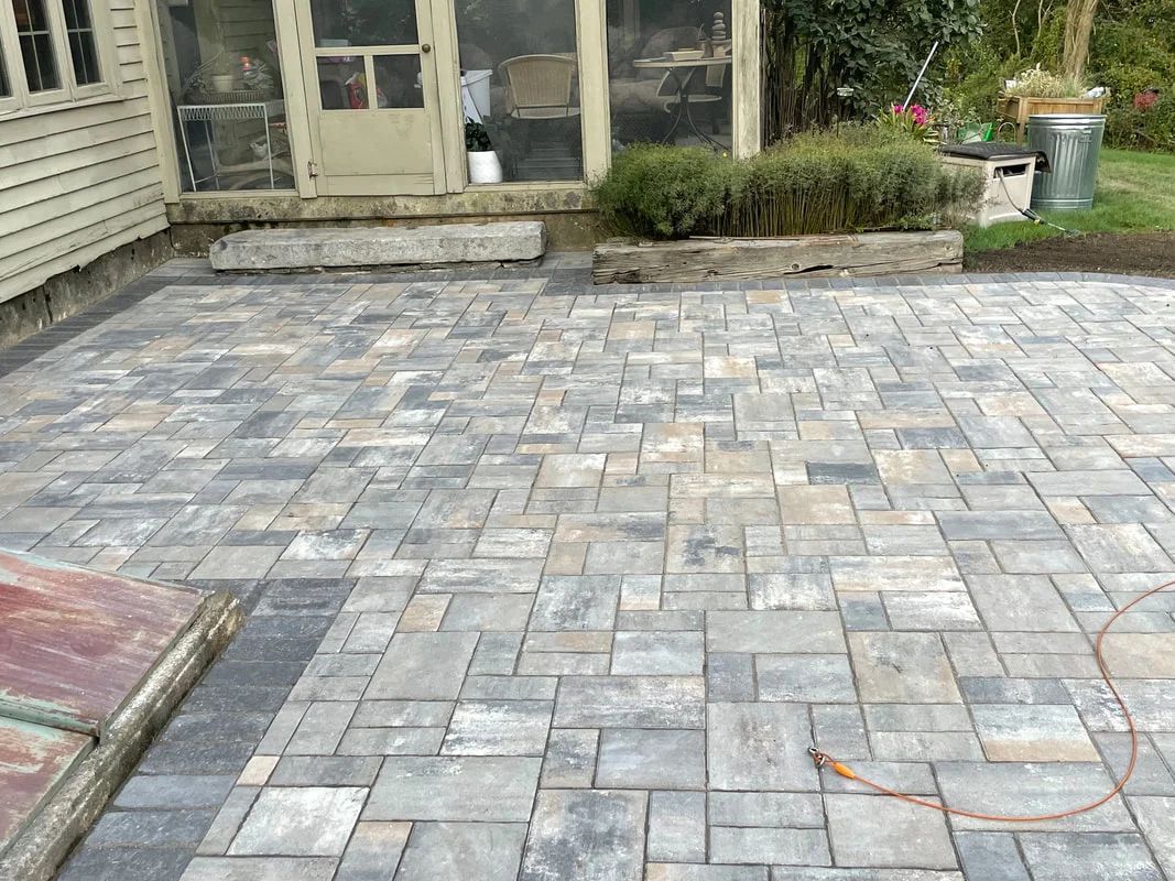 A brick patio is being built in front of a house.