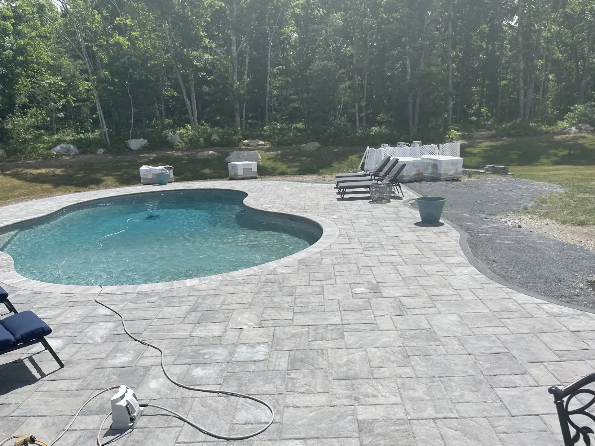 A large swimming pool is surrounded by a patio and chairs.