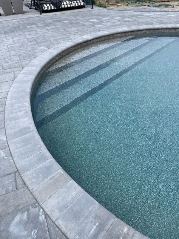 A close up of a swimming pool with steps surrounding it.