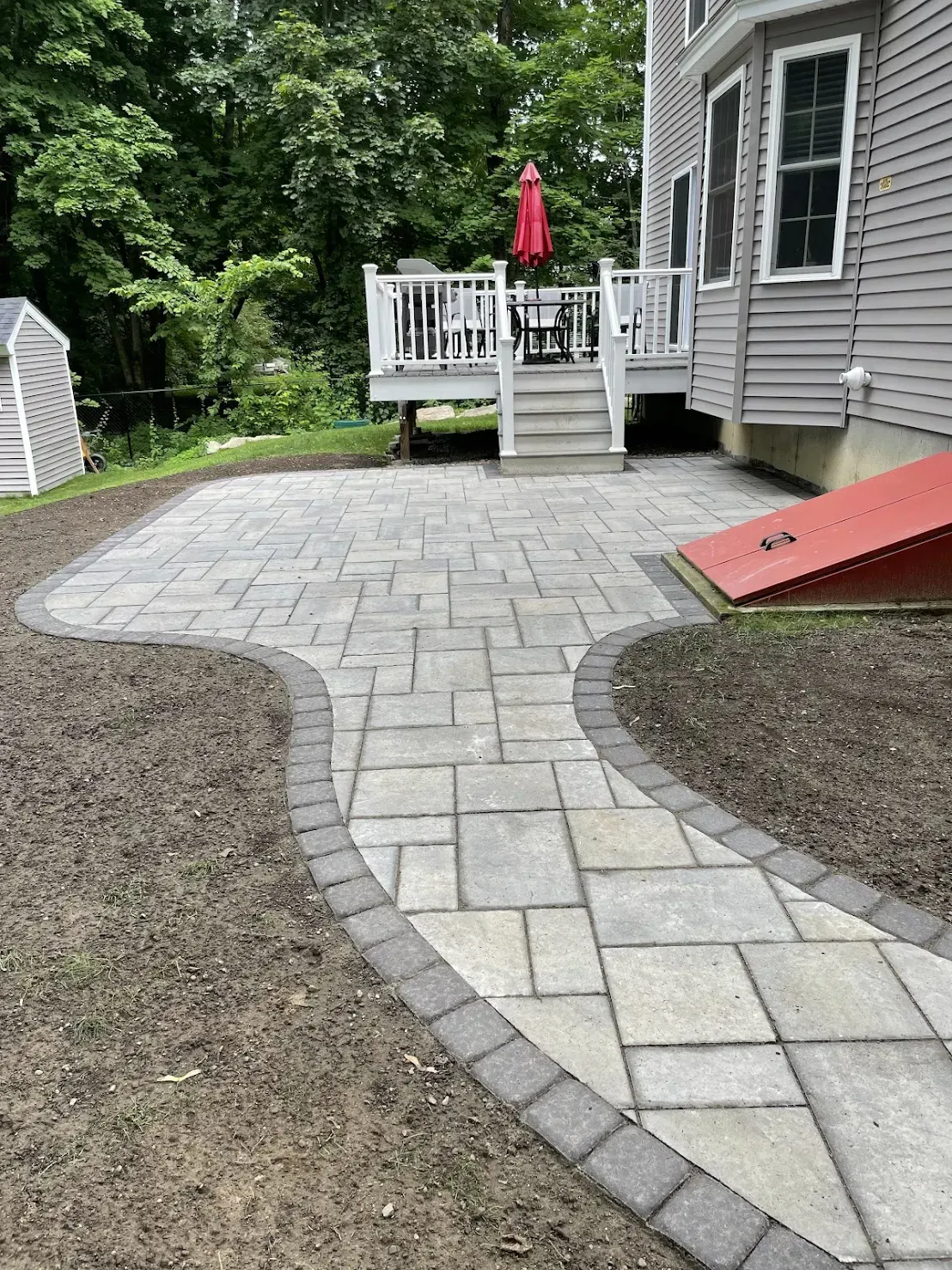 A walkway leading to a patio with a deck and umbrella.