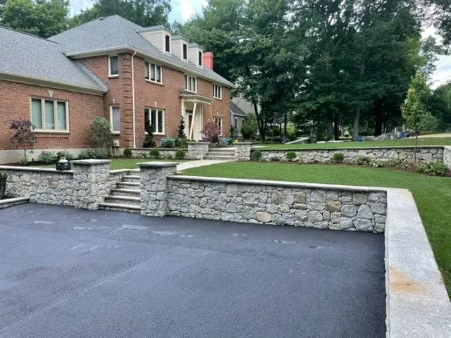 A large brick house with a stone wall in front of it.