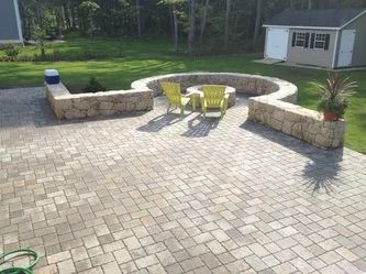 A patio with a fire pit and chairs in the middle of it.