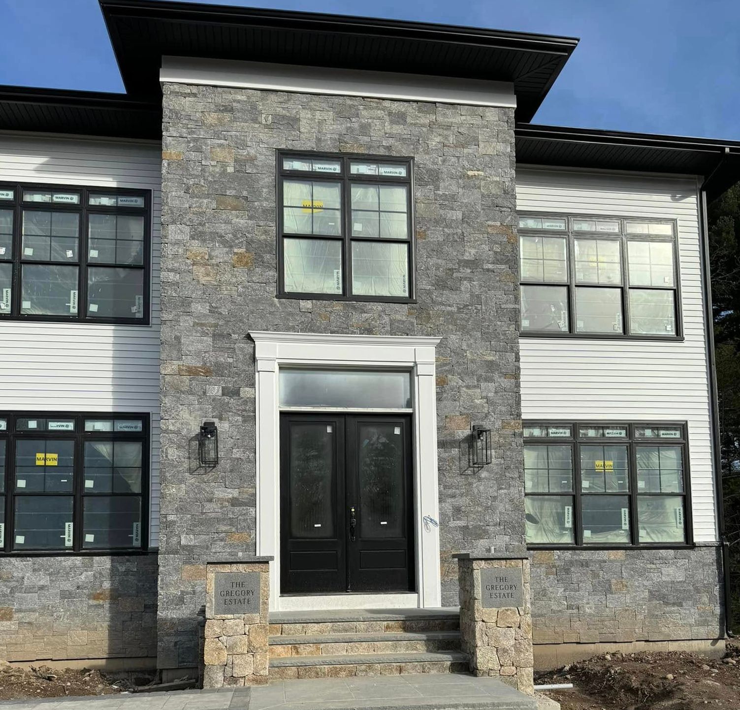 A large house with a stone facade and black windows