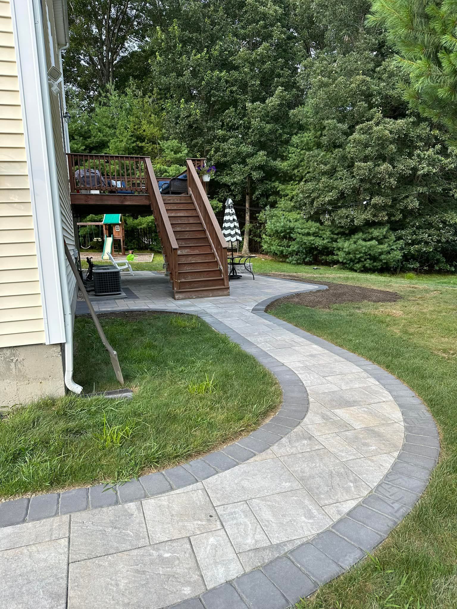 A walkway leading to a house with a deck and stairs.
