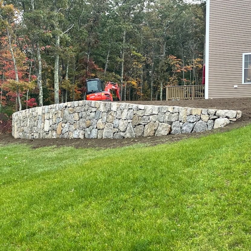 A large stone wall is being built in front of a house.