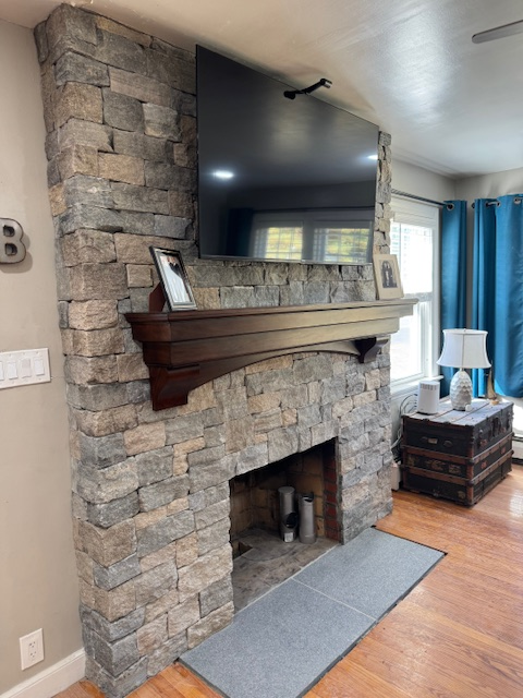A living room with a stone fireplace and a flat screen tv