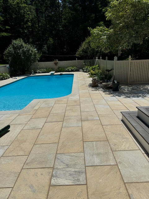 A large swimming pool is surrounded by a tiled patio