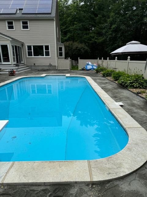 A large swimming pool with a house in the background
