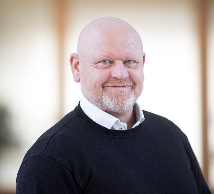 En skaldet mand med skæg iført en sort sweater