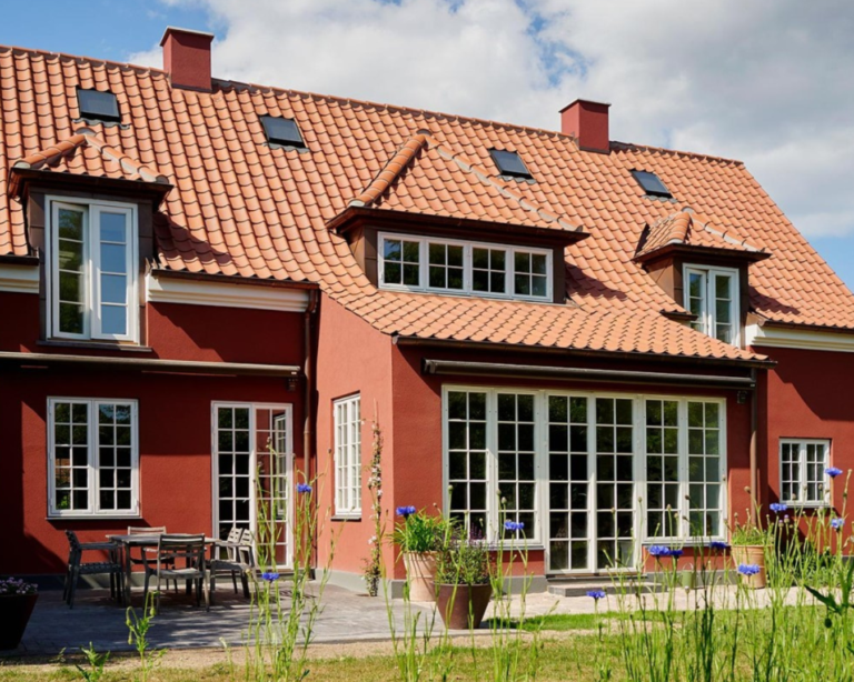 Et stort rødt hus med hvide vinduer og rødt tegltag