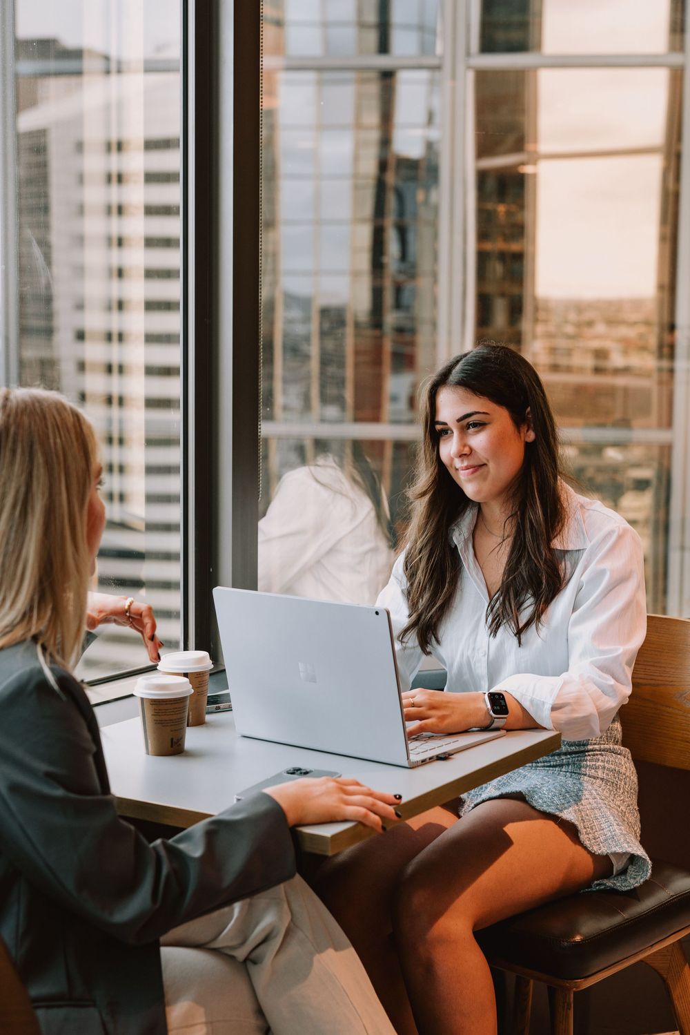 A woman in a suit is sitting at a table with a laptop.