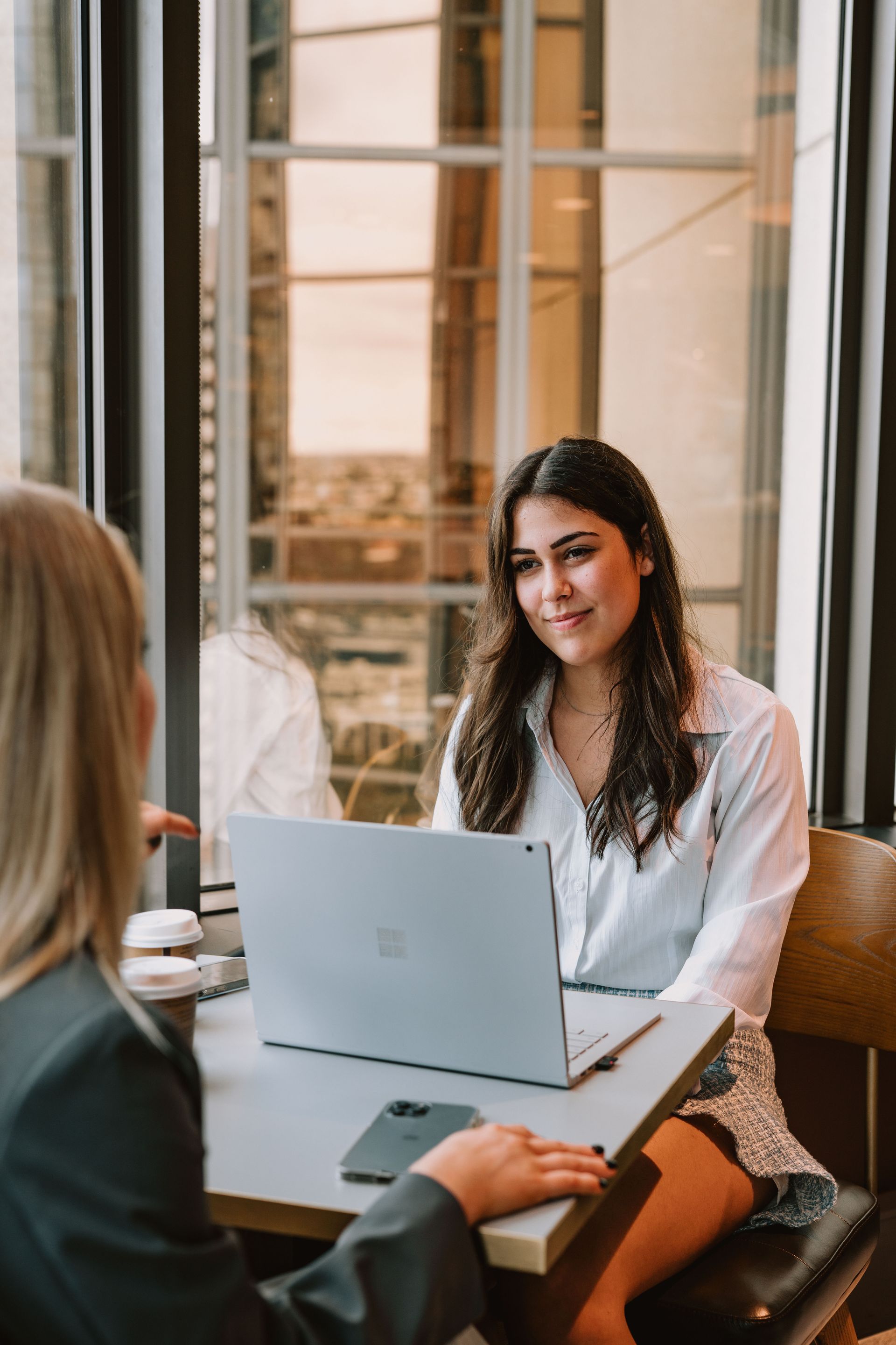 Three women are walking down a sidewalk holding hands.