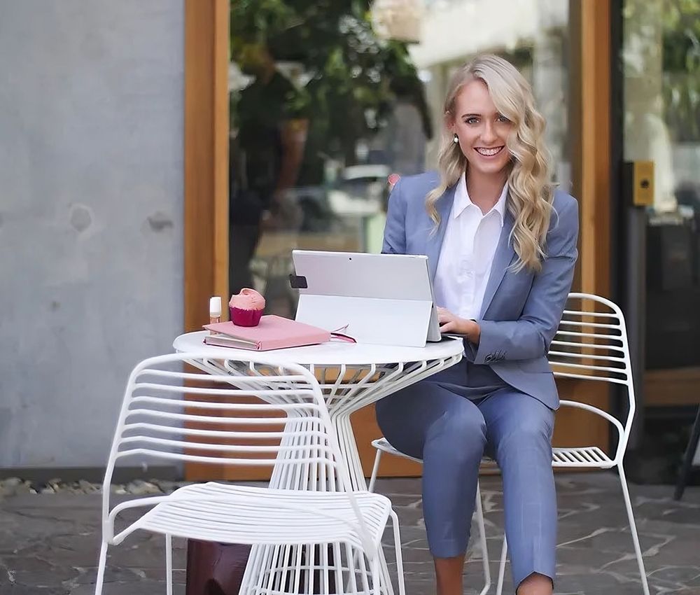 A woman in a suit is sitting at a table with a laptop.