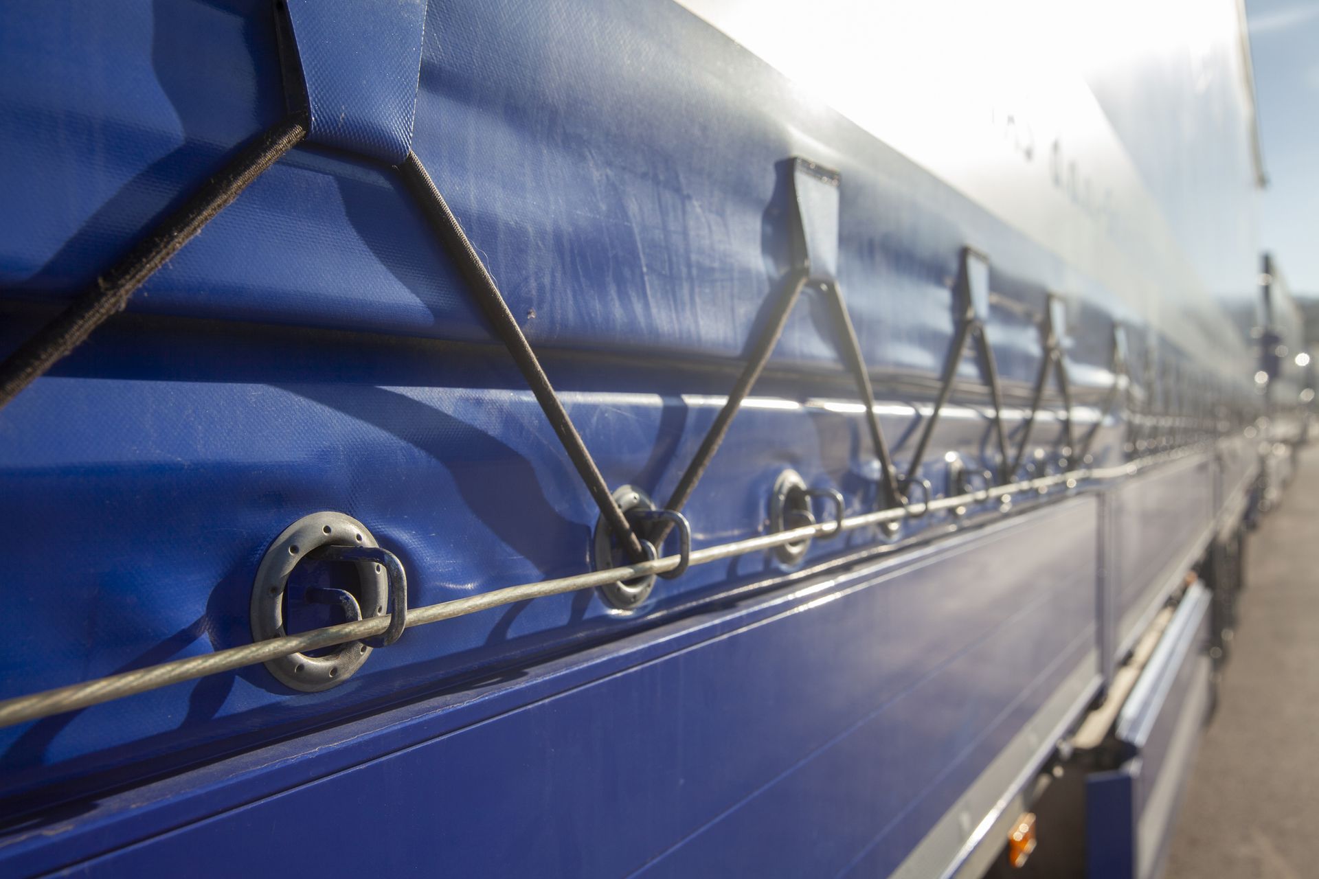 Blue and white truck side with a tarp and metal rings.