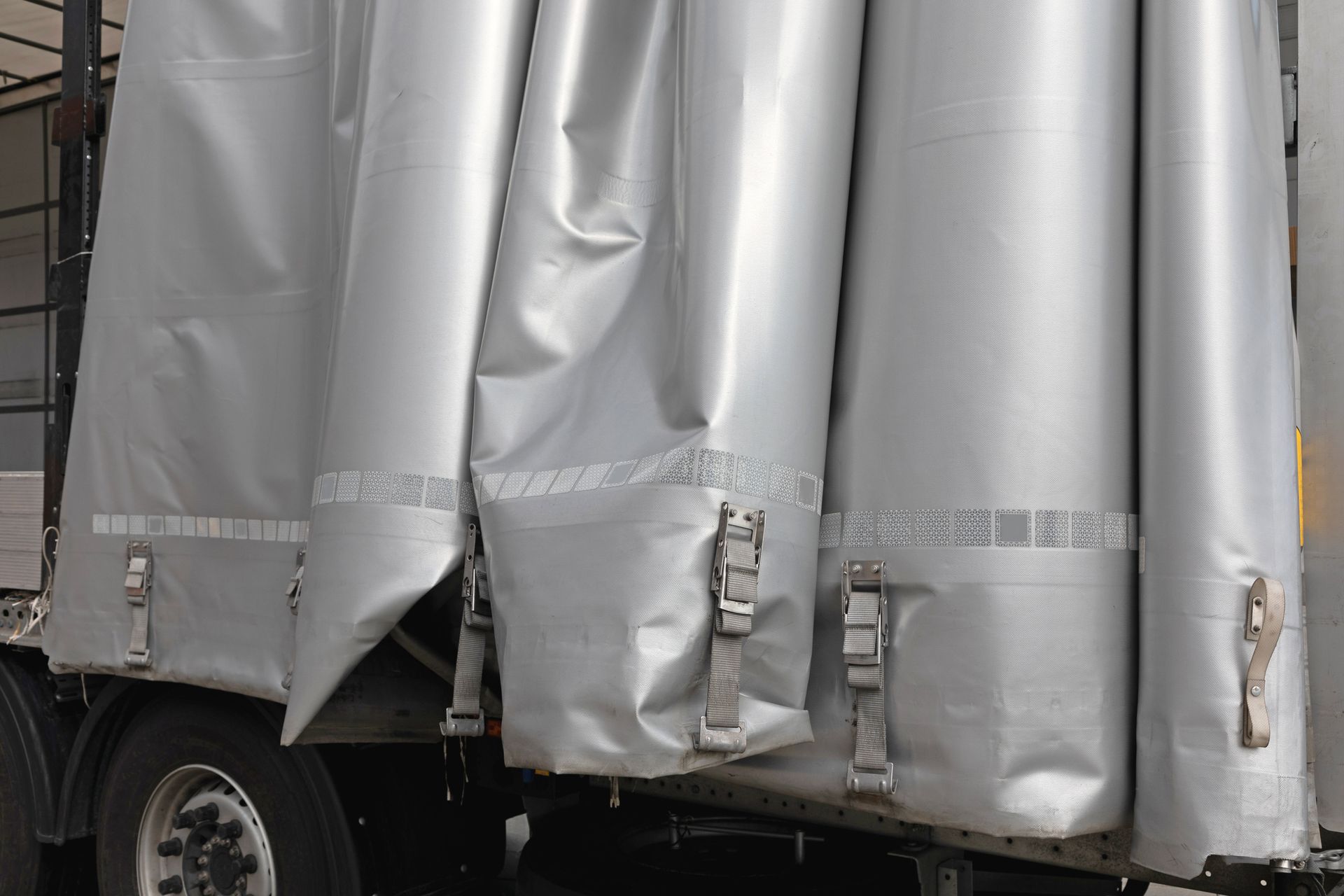 Gray semi-truck curtain side with metal buckles.