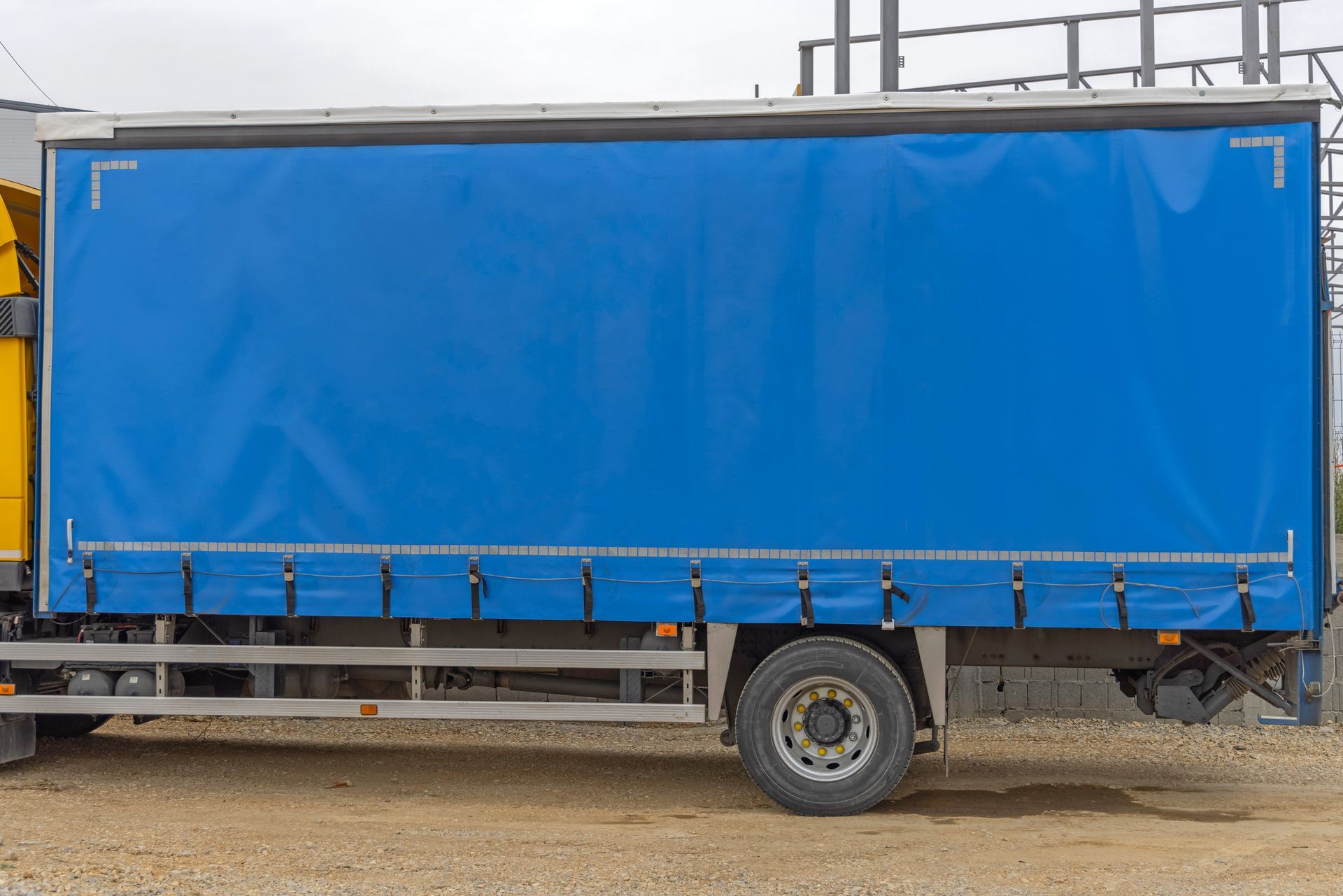 Blue tarp-covered truck side, parked on dirt.