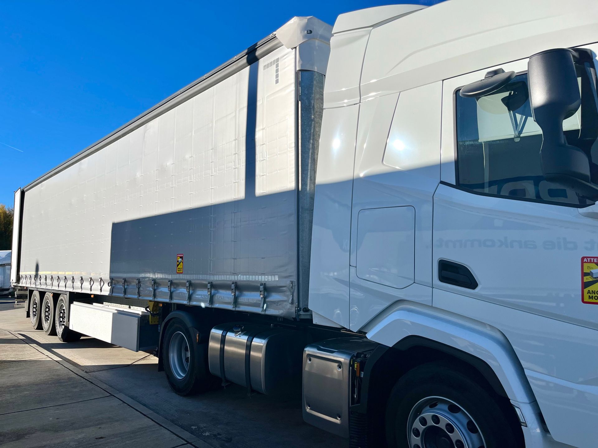 White semi-truck with trailer parked on a sunny day.
