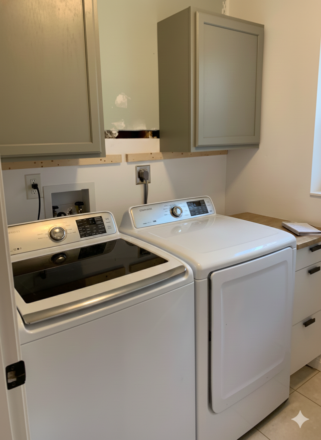 Laundry room with white washer, dryer, gray cabinets, and beige walls.