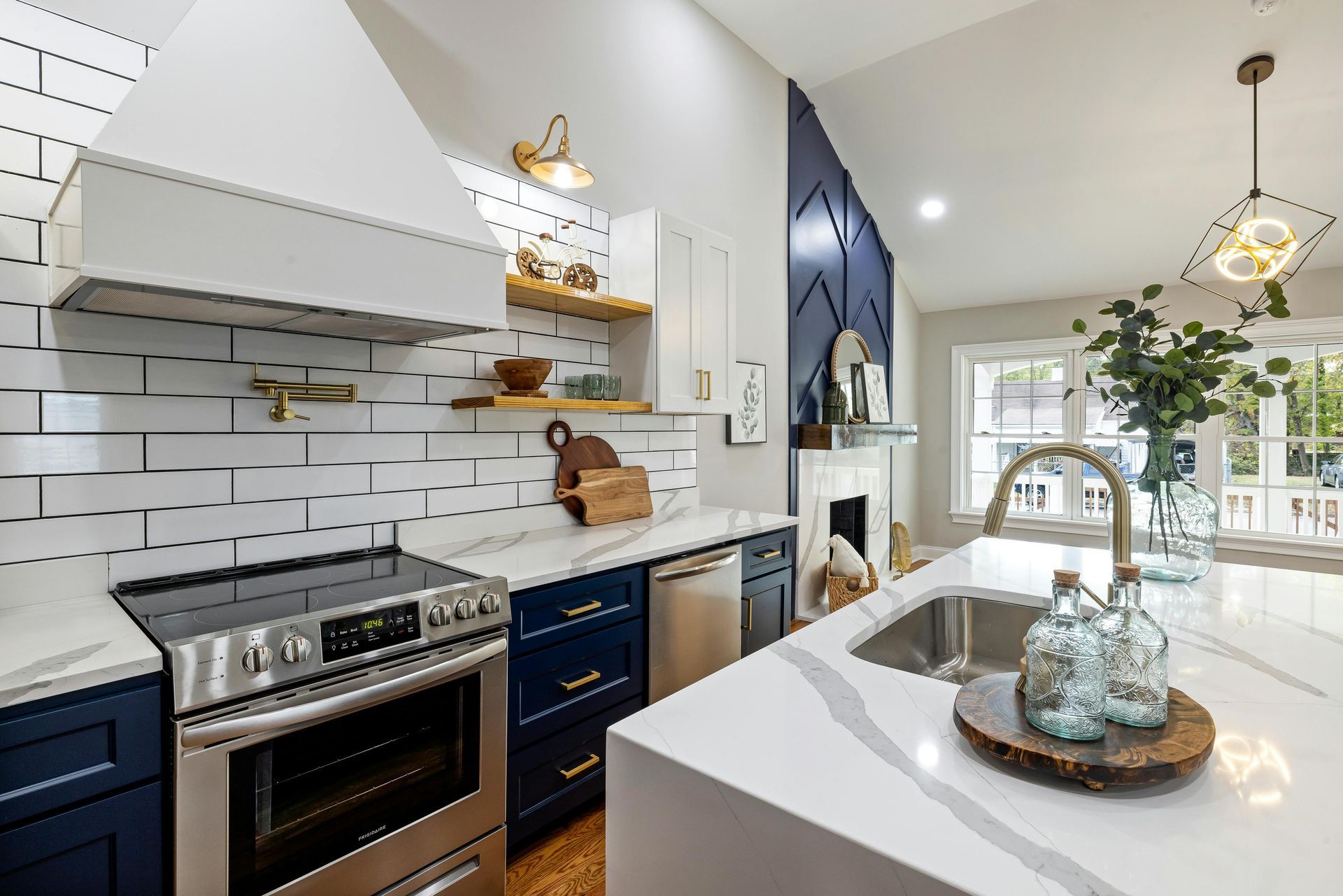 Modern kitchen with blue cabinets, white countertops, stainless steel appliances, and a large island.