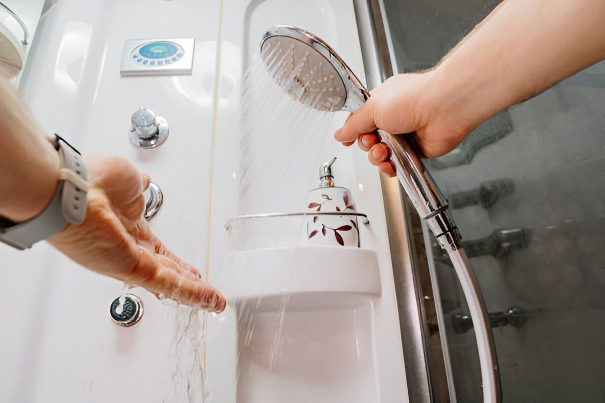 A person is holding a shower head in a bathroom.