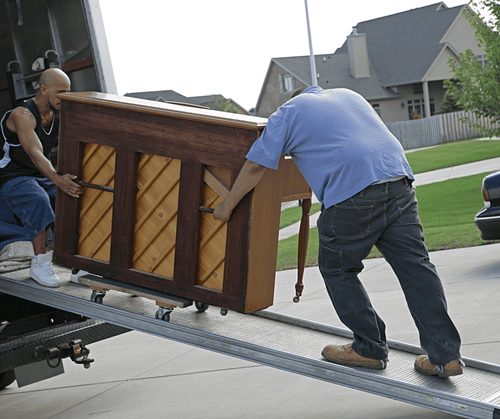 two man  dragging piano up a ramp into a truck