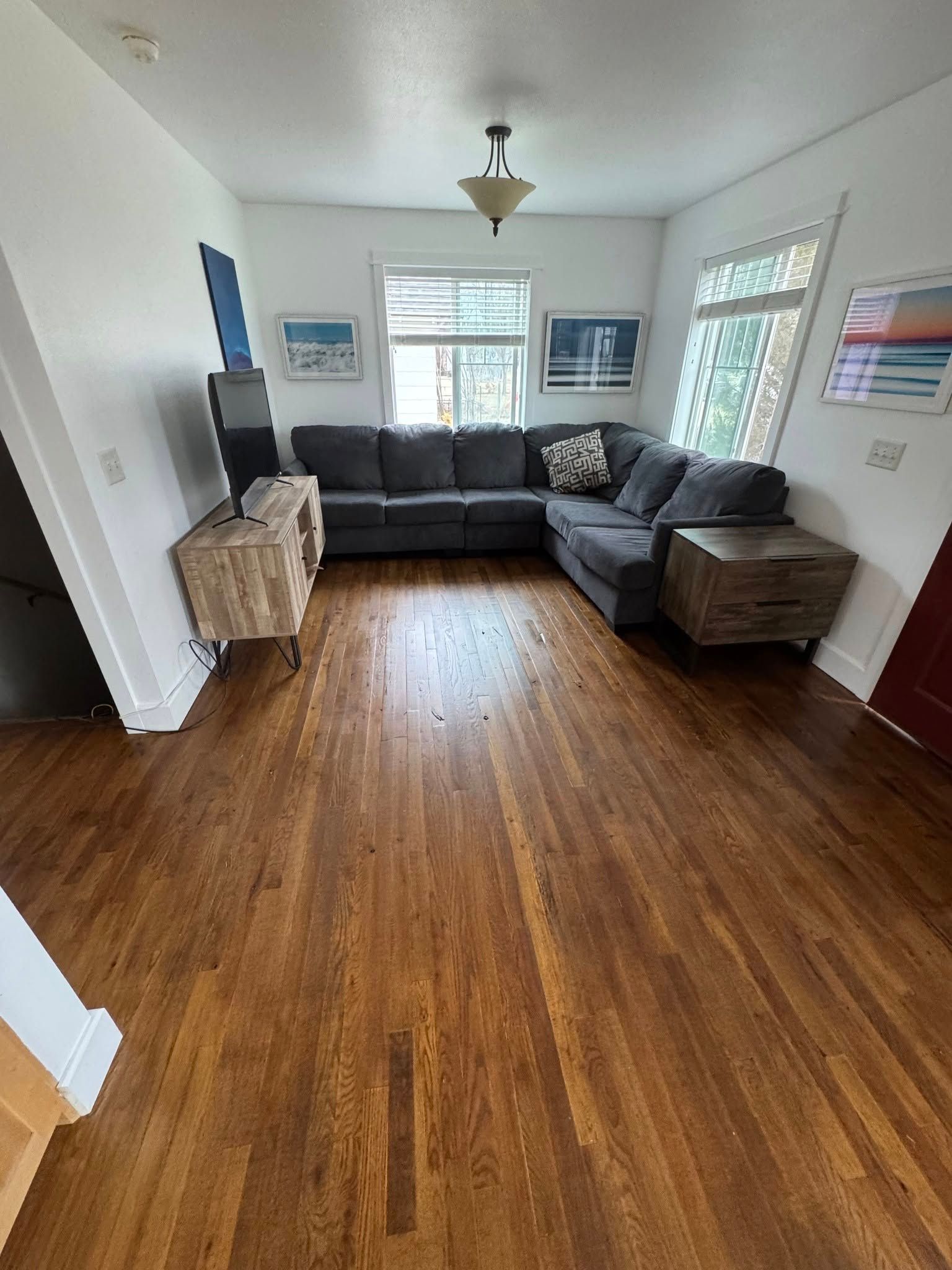 Living room with gray sectional sofa, wood floor, and two wood side tables.