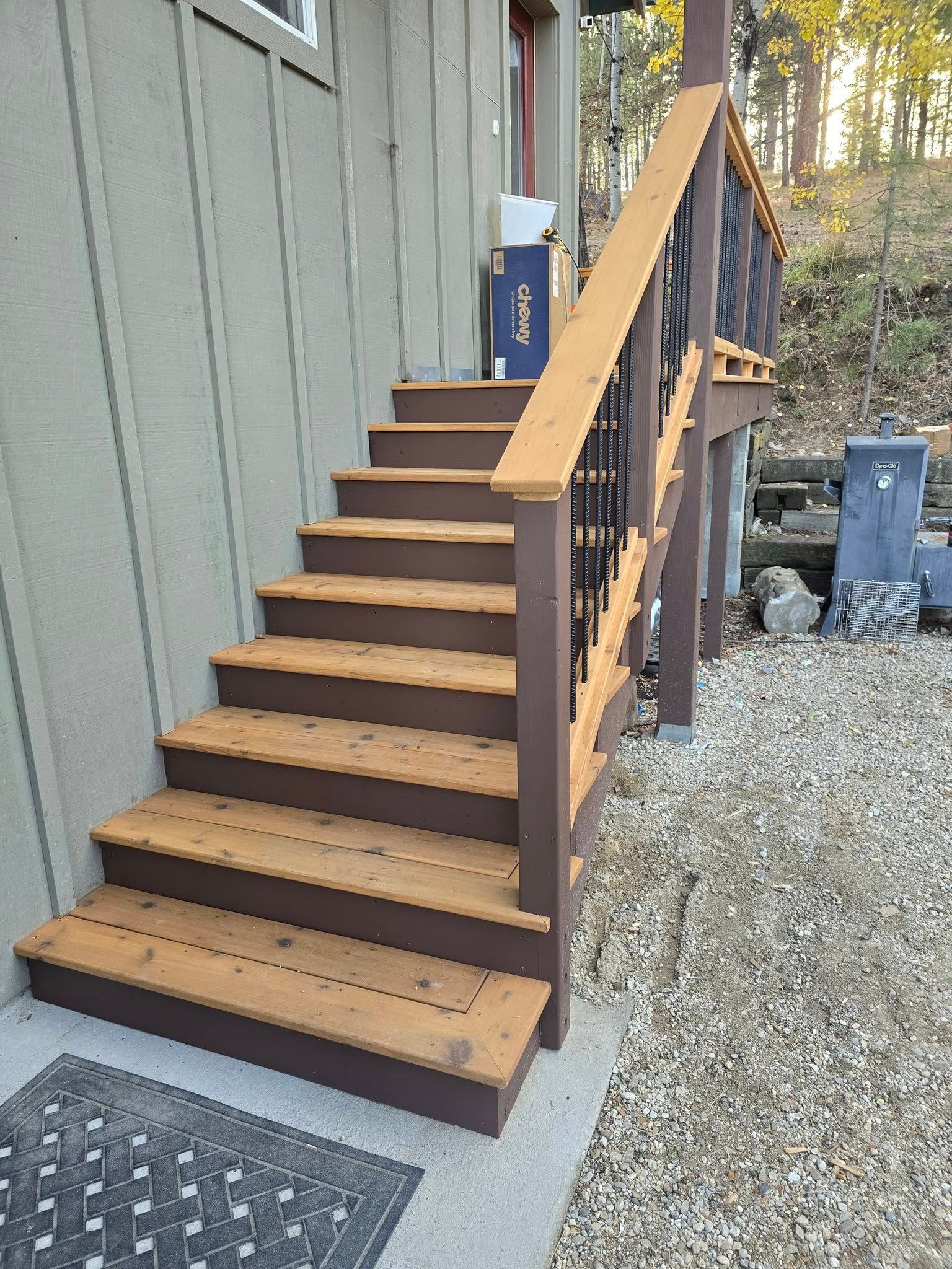 Wooden exterior staircase with brown treads and dark railing leading up to a building.