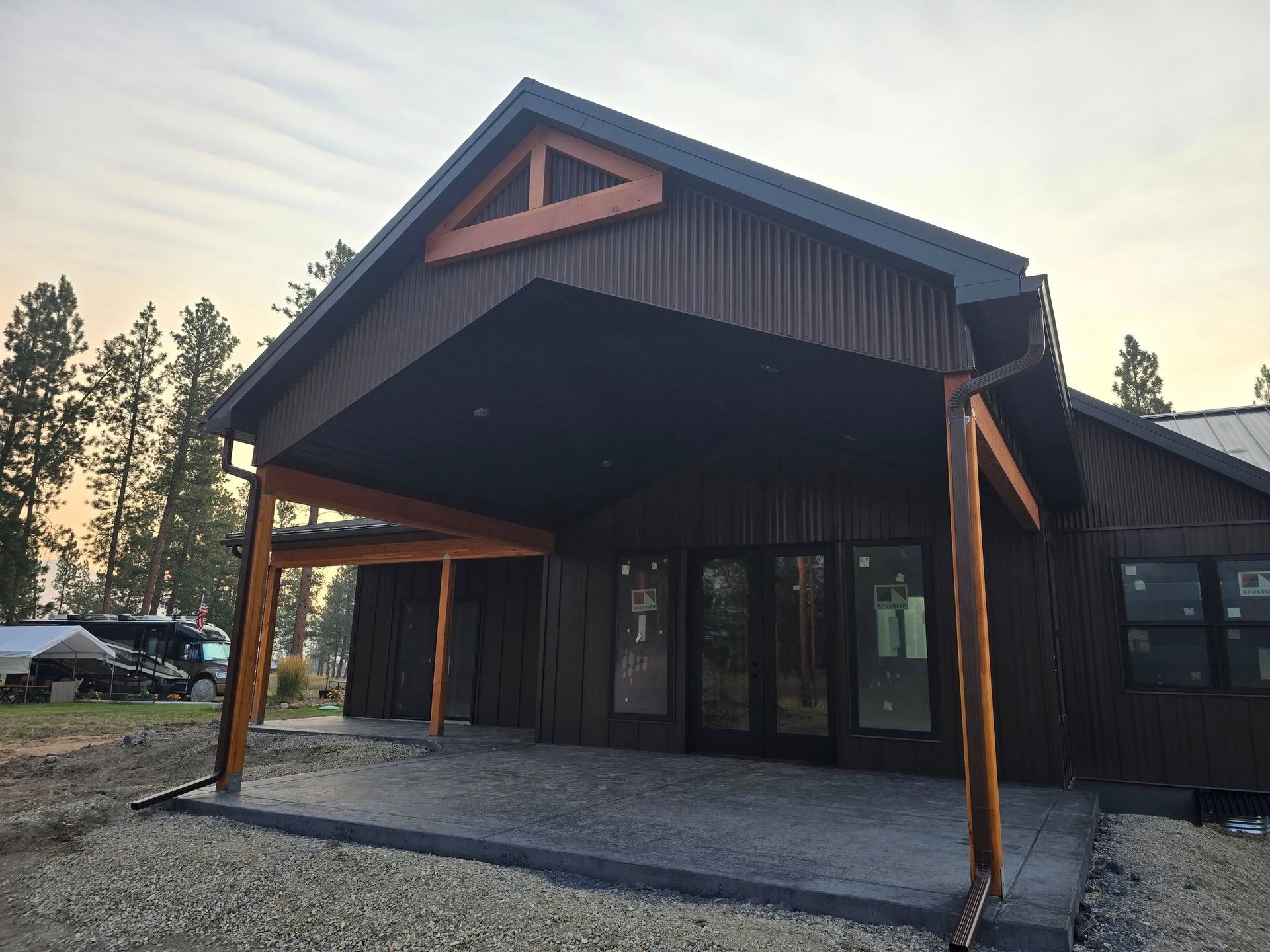 Brown building with a covered entrance and wooden supports. Cloudy sky in background.