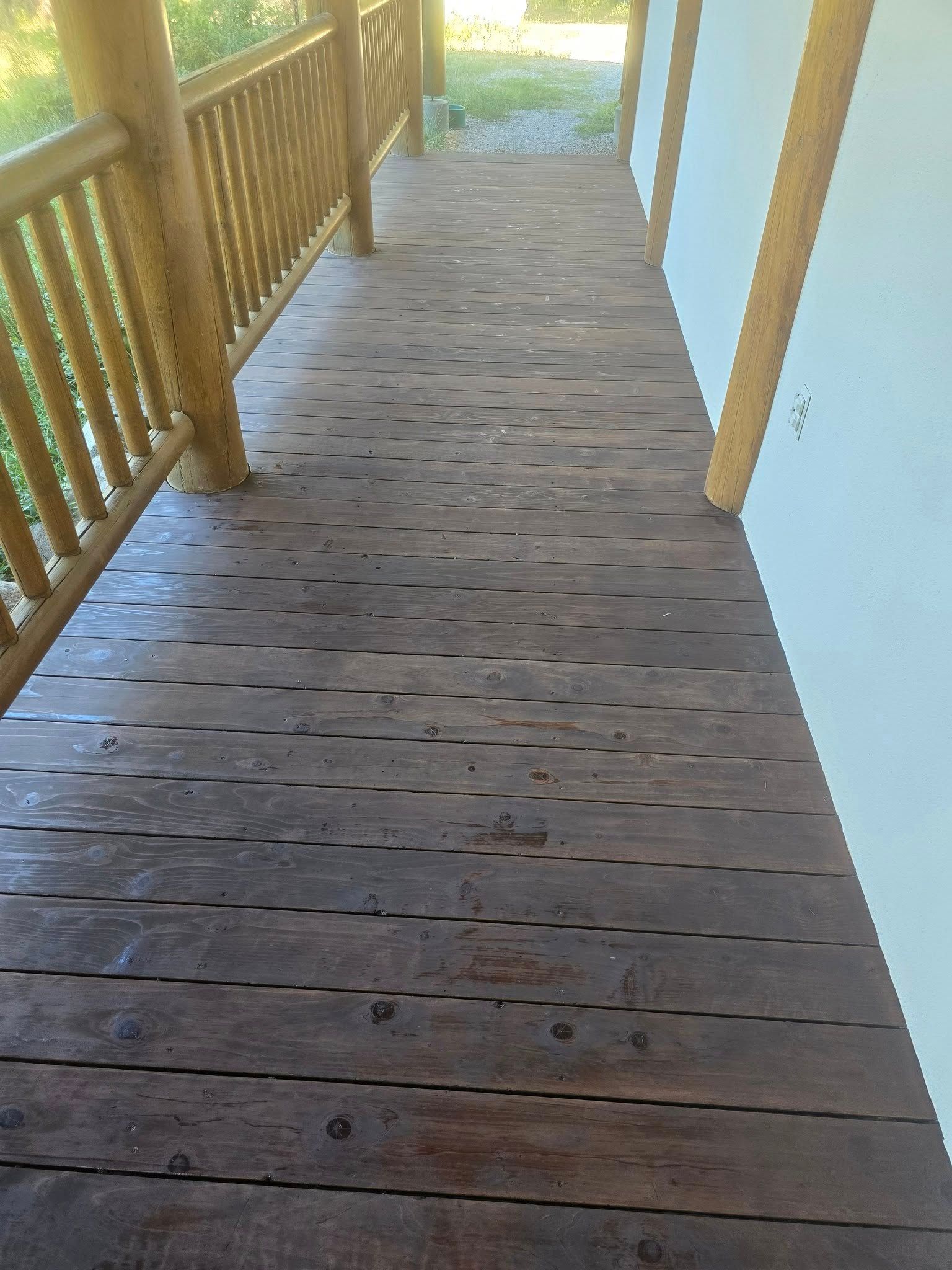 Wooden porch with dark wood planks and log railings.